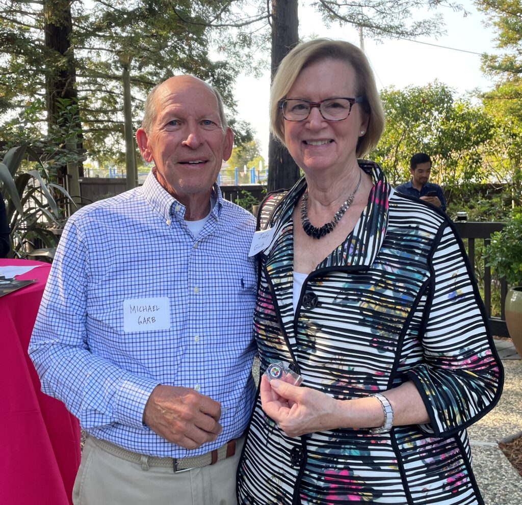 Couple smiling at camera, holding Visionary lapel pins.